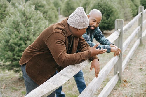 黑人父亲跟无法认出的儿子在农村的篱笆旁交谈 · 免费素材图片