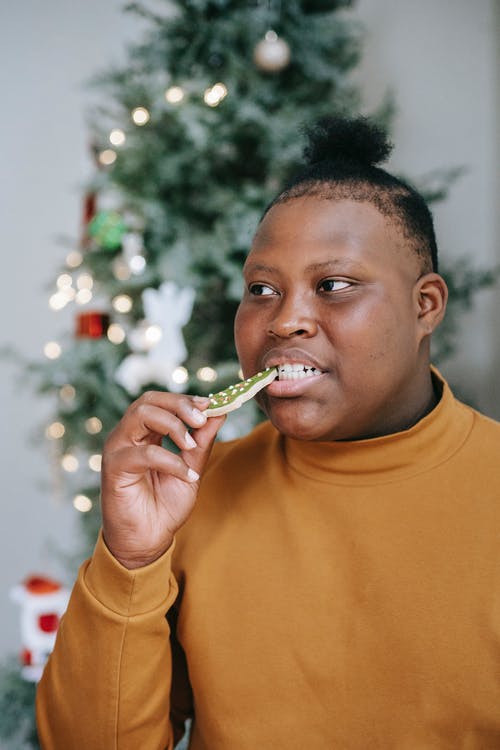 黑人青少年在家附近枞树上吃圣诞饼干 · 免费素材图片
