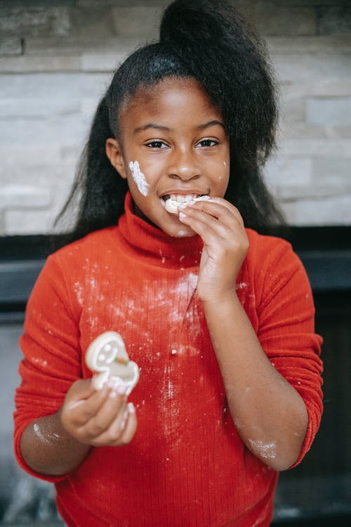 在圣诞节假期期间吃姜饼饼干的迷人肮脏的黑人女孩 · 免费素材图片