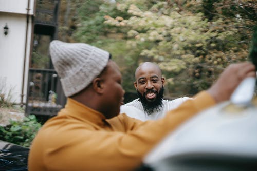 微笑的时髦人说话与黑人儿子在树附近 · 免费素材图片