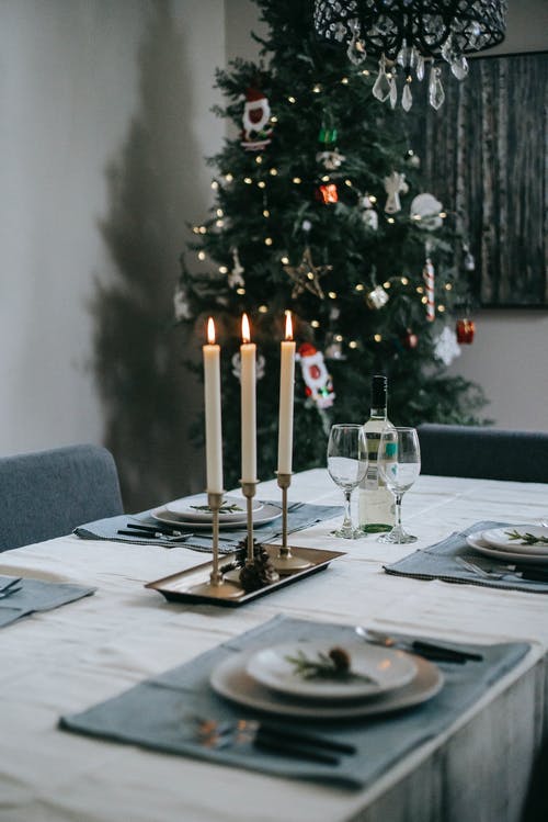宴会桌上用燃烧的蜡烛，附近的圣诞树 · 免费素材图片