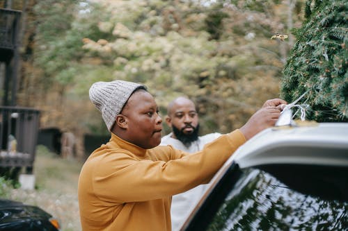 黑人青少年绑枞树在父亲附近的车顶上 · 免费素材图片
