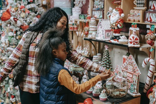 快乐的黑人母亲带着女儿在商店里选择纪念品 · 免费素材图片