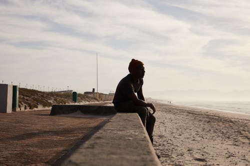 黑人男子坐在石边框上 · 免费素材图片