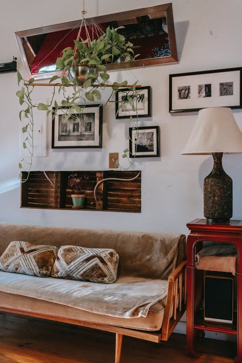 沙发和小展示柜，壁灯旁装有优雅的灯，在家中装饰有裱框的图片 · 免费素材图片