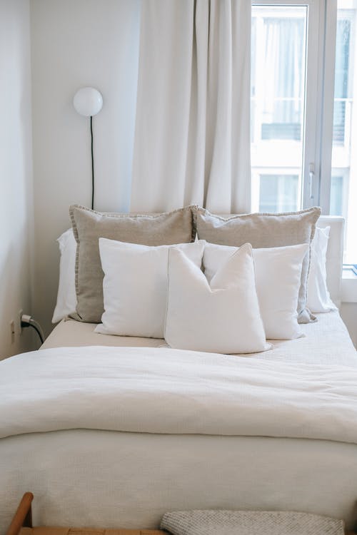 舒适的床，枕头在房子的窗户附近 · 免费素材图片