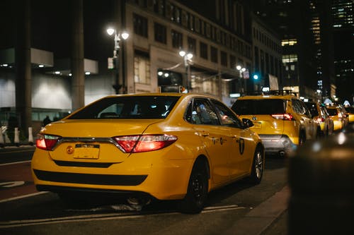 晚上沿着路行驶的黄色出租车 · 免费素材图片