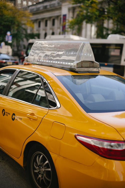 在城里的街道上驾驶的黄色出租车 · 免费素材图片