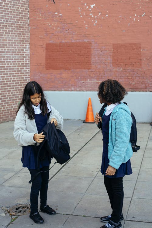 不同的女学生站在学校大楼附近的背包 · 免费素材图片