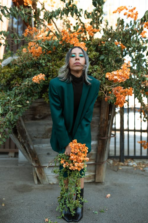 拿着西装的花束绿色西装外套的女人 · 免费素材图片