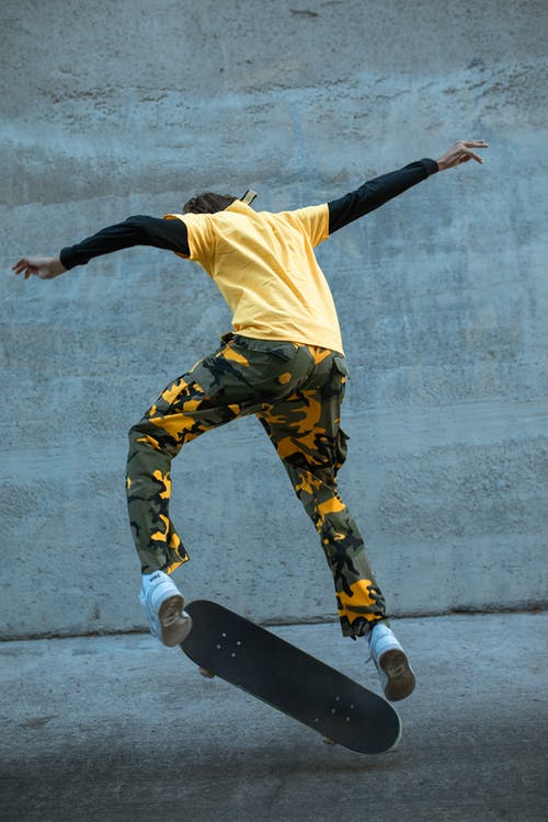 黄色衬衫和黑色的裤子，穿着黑色的鞋子，在灰色的水泥地板上跳跃的人 · 免费素材图片
