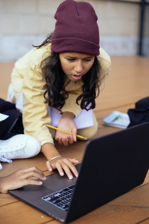 西班牙裔女学生在作物朋友在户外附近的笔记本电脑上上网 · 免费素材图片