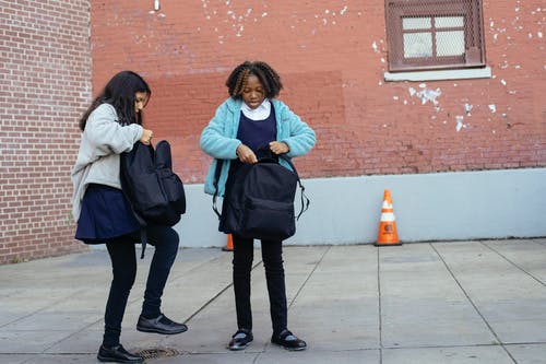 多民族的女学生站在学校外面和关闭背包 · 免费素材图片