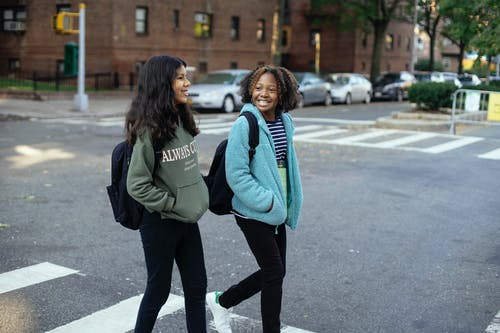 快乐的多民族女友背着背包谈城市道路 · 免费素材图片