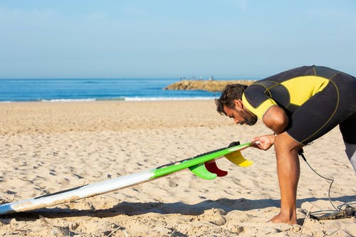 潜水衣的人准备冲浪板的冲浪板在海滩上 · 免费素材图片