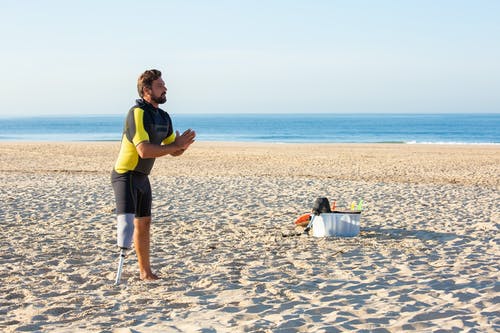 在沙滩上热身的假肢的男人 · 免费素材图片