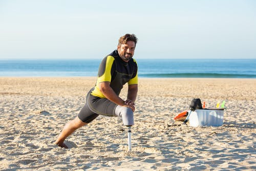 男人做热身运动在海滩上 · 免费素材图片