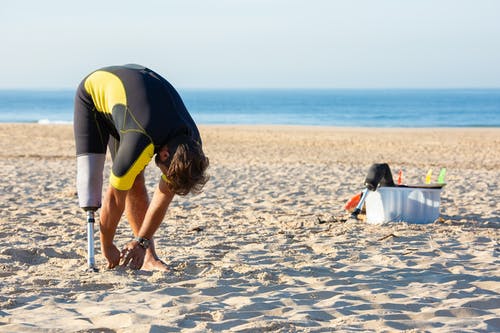 假腿在海滩上热身的成年男子 · 免费素材图片