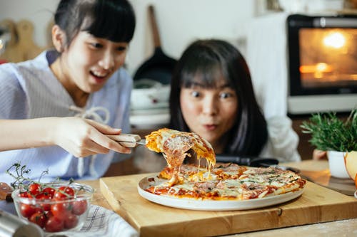 白色长袖衬衫吃披萨的女孩 · 免费素材图片