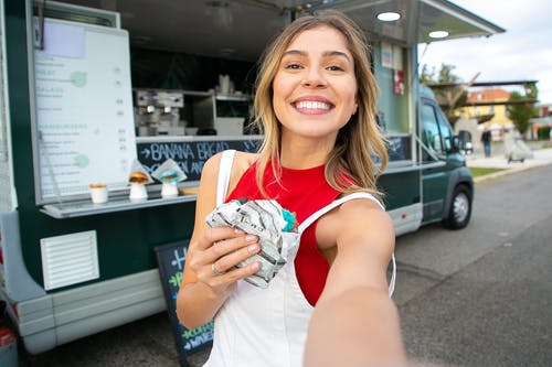 甜甜圈采取自拍照在食品站附近的幸福女人 · 免费素材图片