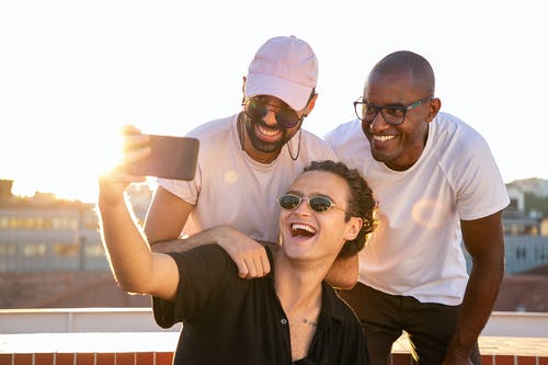 性格开朗的年轻多民族男人笑着在阳光下采取自拍照 · 免费素材图片