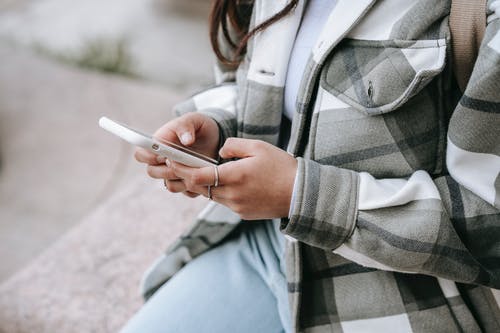 拿着智能手机的灰色和黑色格子外套的女人 · 免费素材图片