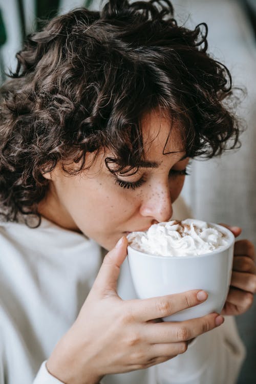 拿着白色陶瓷杯子的白衬衫的女人 · 免费素材图片