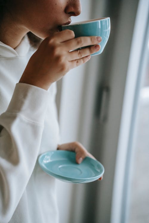 拿着蓝色塑料容器的白色长袖衬衫的女人 · 免费素材图片