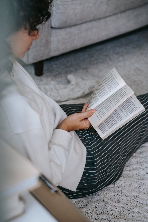 黑色和白色条纹的裙子阅读书中的女人 · 免费素材图片