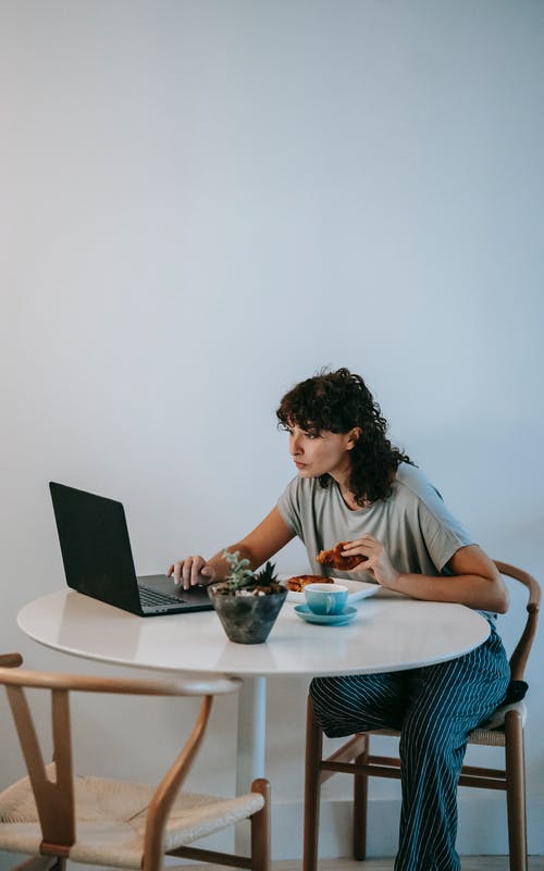 坐在餐桌旁使用macbook的白衬衫的女人 · 免费素材图片