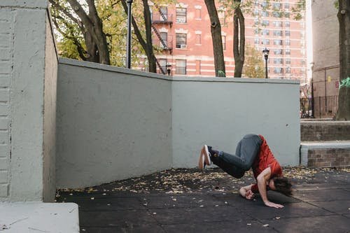 躺在水泥地上的红色t恤和蓝色牛仔牛仔裤的男人 · 免费素材图片