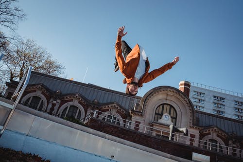 跳上半空中的棕色夹克的男人 · 免费素材图片