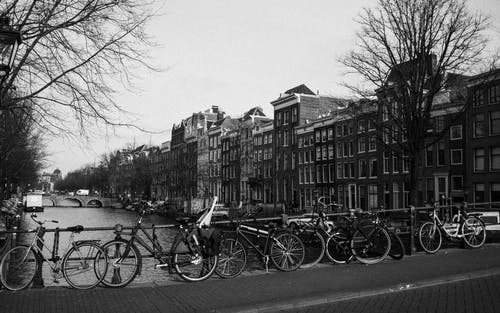 自行车在阴天停在运河和老建筑附近的城市路堤上 · 免费素材图片
