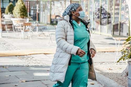 绿色外套和绿色的裤子，站在人行道上的女人 · 免费素材图片