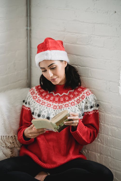 红色和白色的圣诞老人的帽子，拿着本书的女孩 · 免费素材图片