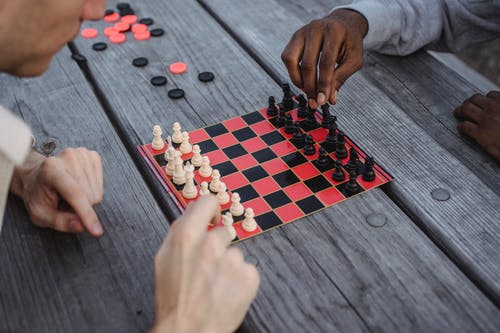 在灰色的木桌上下棋的人 · 免费素材图片