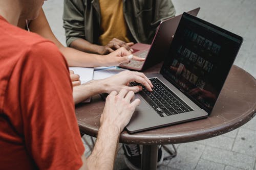 男人和女人坐在椅子上使用macbook Pro · 免费素材图片