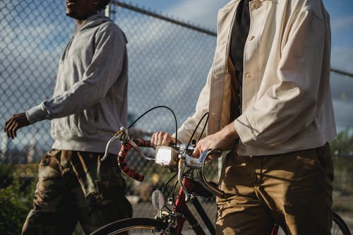 棕色纽扣衬衫和棕色裤子站在红色自行车旁边的人 · 免费素材图片