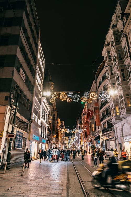 夜间在建筑物之间的街道上行走的人 · 免费素材图片