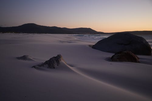 白雪覆盖地面上的黑色岩石形成 · 免费素材图片