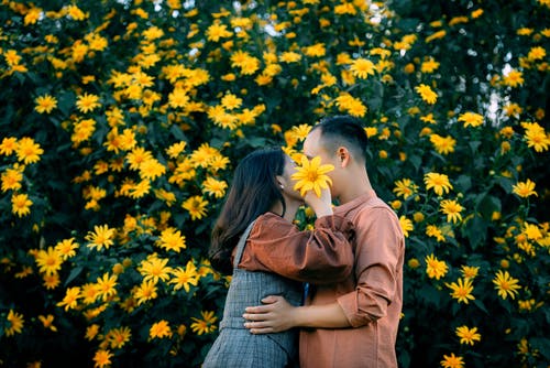 站在黄色的花场上的棕色夹克和蓝色牛仔裙的女人 · 免费素材图片