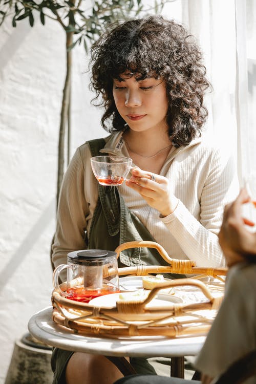 拿着清楚的水杯的白色长袖衬衫的女人 · 免费素材图片