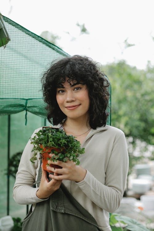 拿着绿色和红色花束的白色长袖衬衫的女人 · 免费素材图片