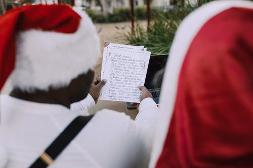 红色圣诞老人衣服的人读在纸的一条消息 · 免费素材图片