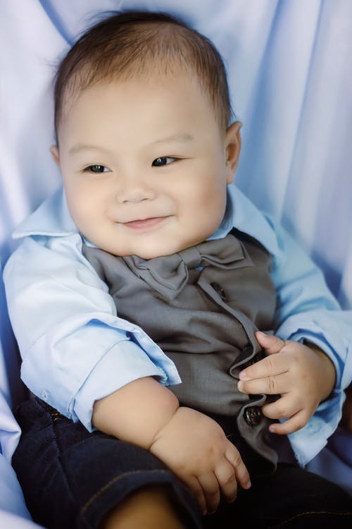 婴儿躺在白色纺织上的蓝色礼服衬衫 · 免费素材图片