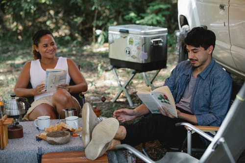 男人和女人坐在椅子上看书 · 免费素材图片