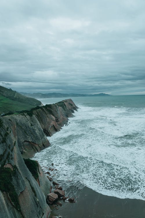 海边的绿色和棕色岩层 · 免费素材图片