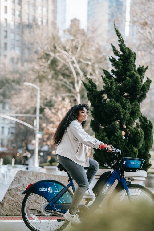 白色长袖衬衫骑在蓝色摩托车上的女人 · 免费素材图片