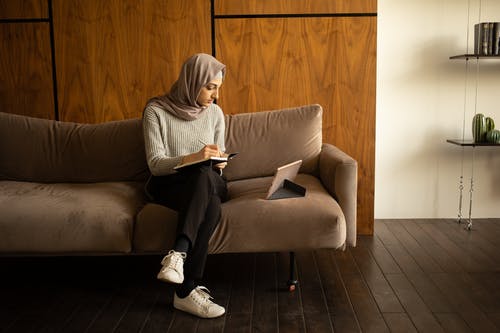 白头巾的女人坐在棕色的沙发上 · 免费素材图片