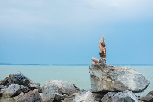 坐在海边的灰色岩石上的棕色比基尼的女人 · 免费素材图片